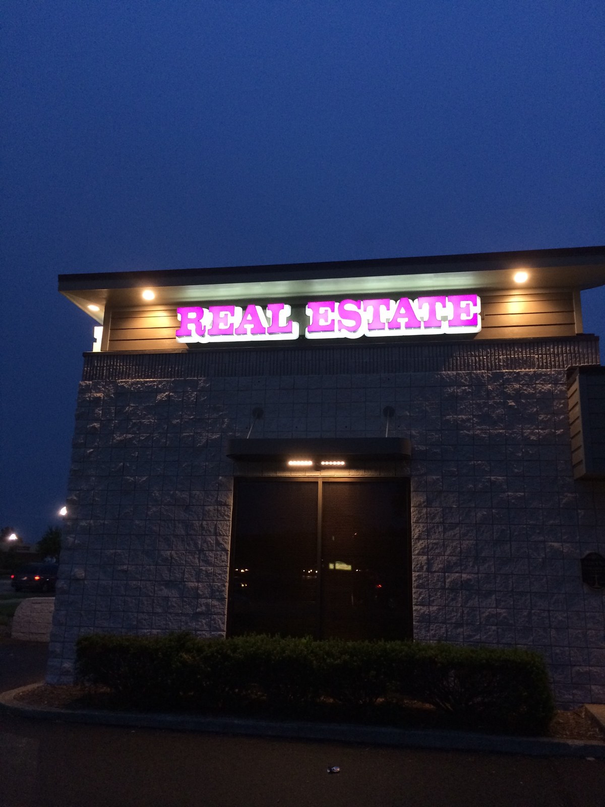 Chris Karapatsakis Real Estate office sign at dusk